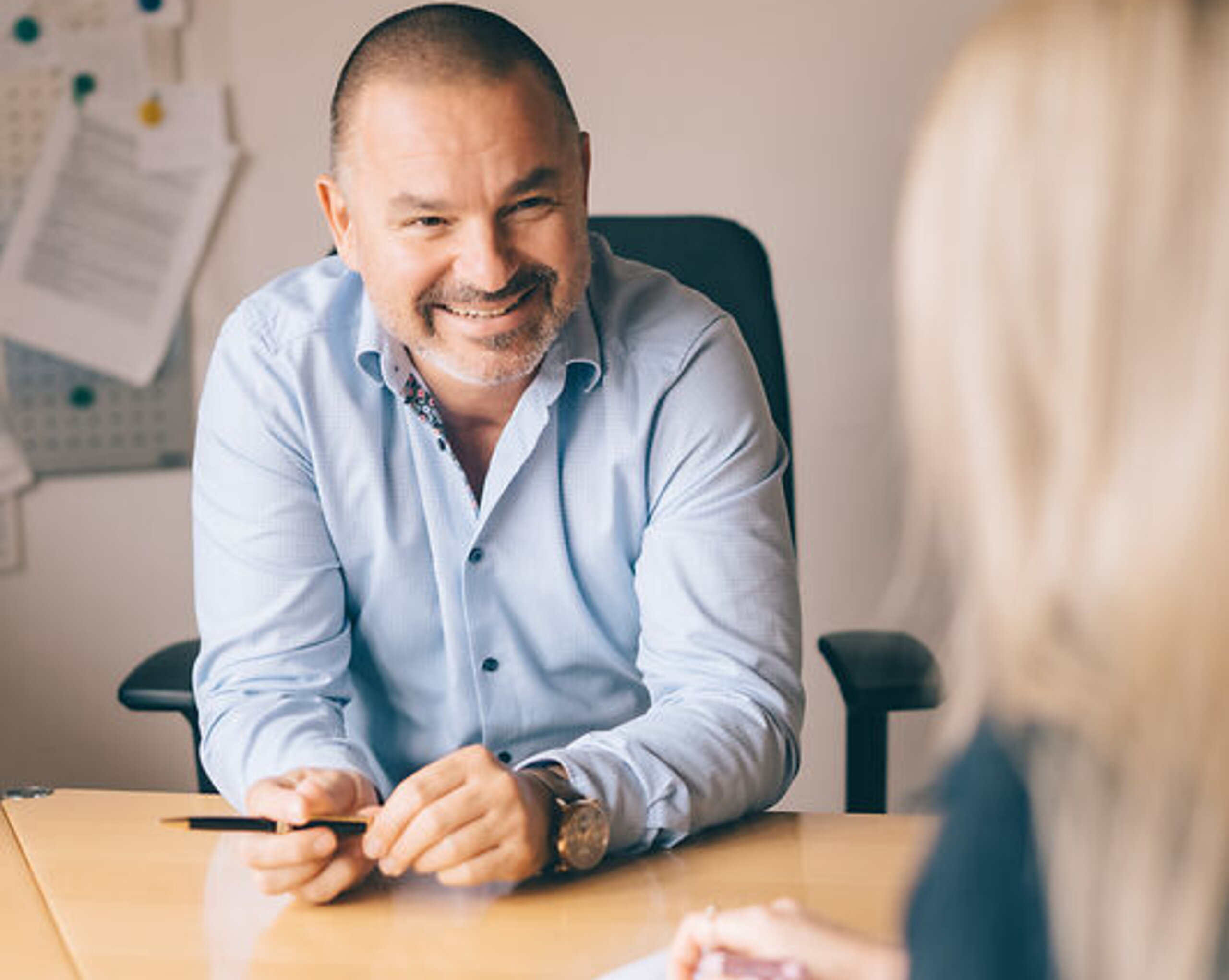 Maximilian Koehler Dr. Köhler sitzt lächeln am Schreibtisch mit einer Patientin.