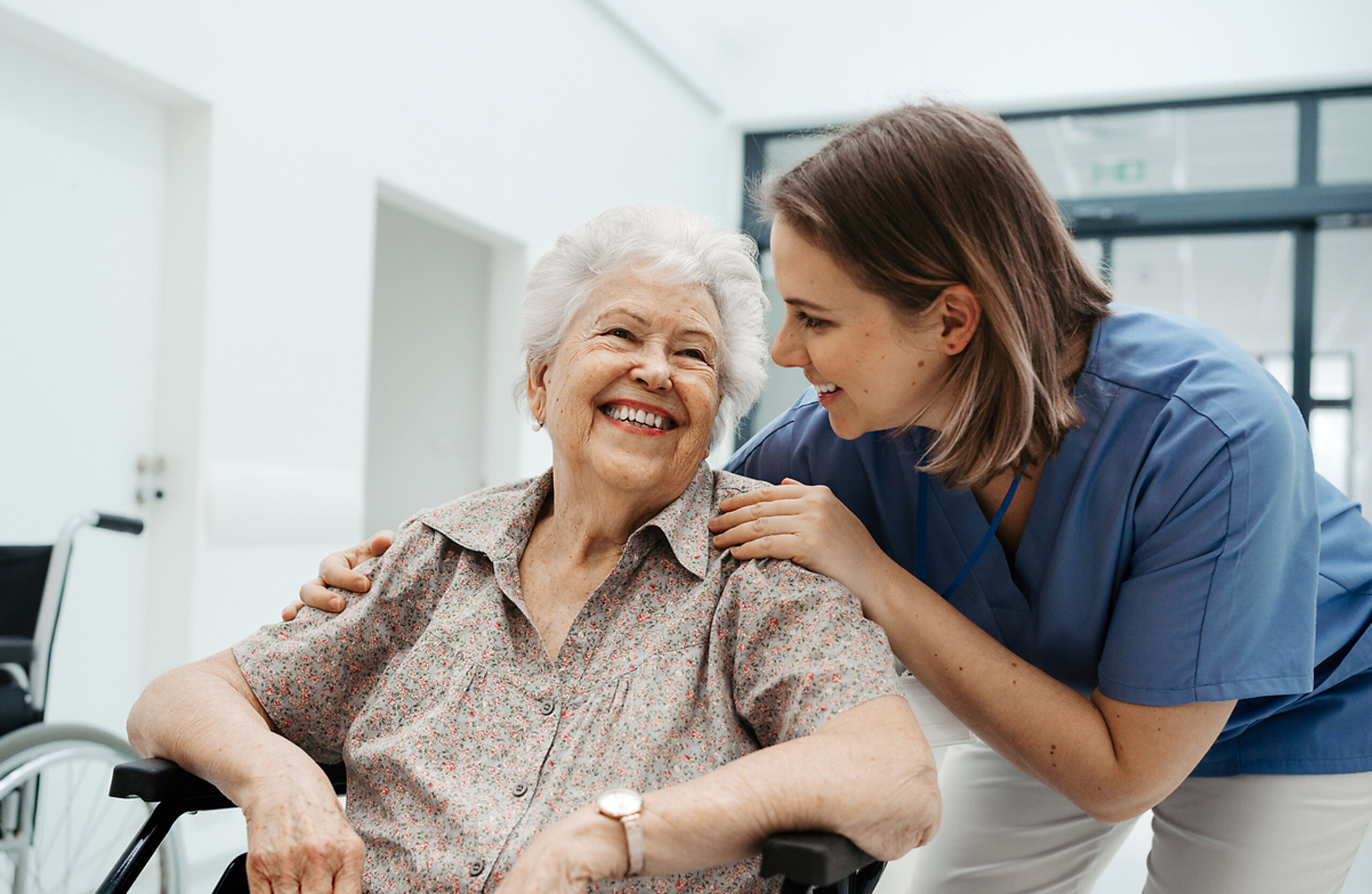 Patientin im Rollstuhl mit Pflegerin Eine ältere Patientin im Rollstuhl wird freundlich von einer Pflegerin betreut.