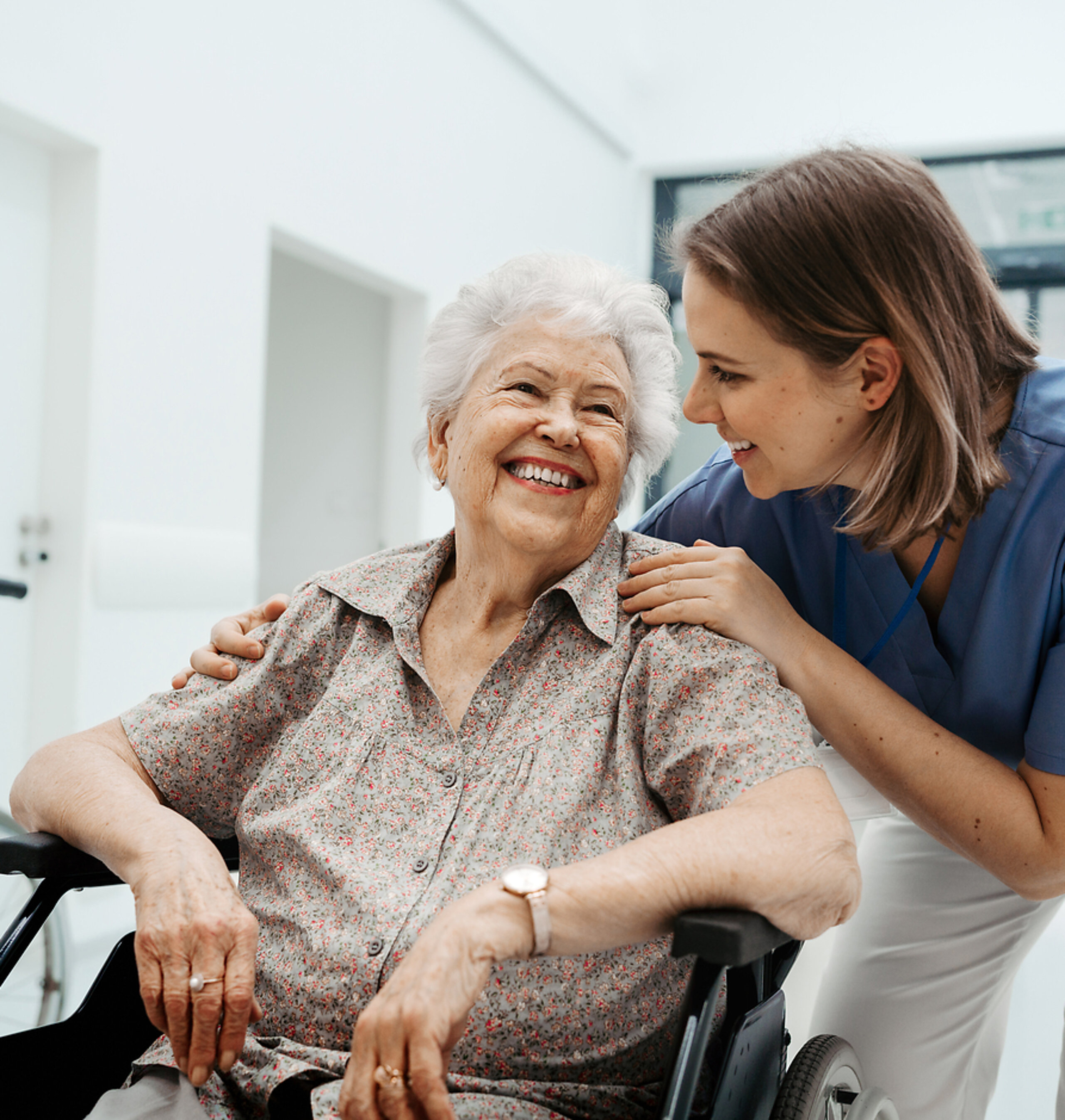 Patientin im Rollstuhl mit Pflegerin Eine ältere Patientin im Rollstuhl wird freundlich von einer Pflegerin betreut.