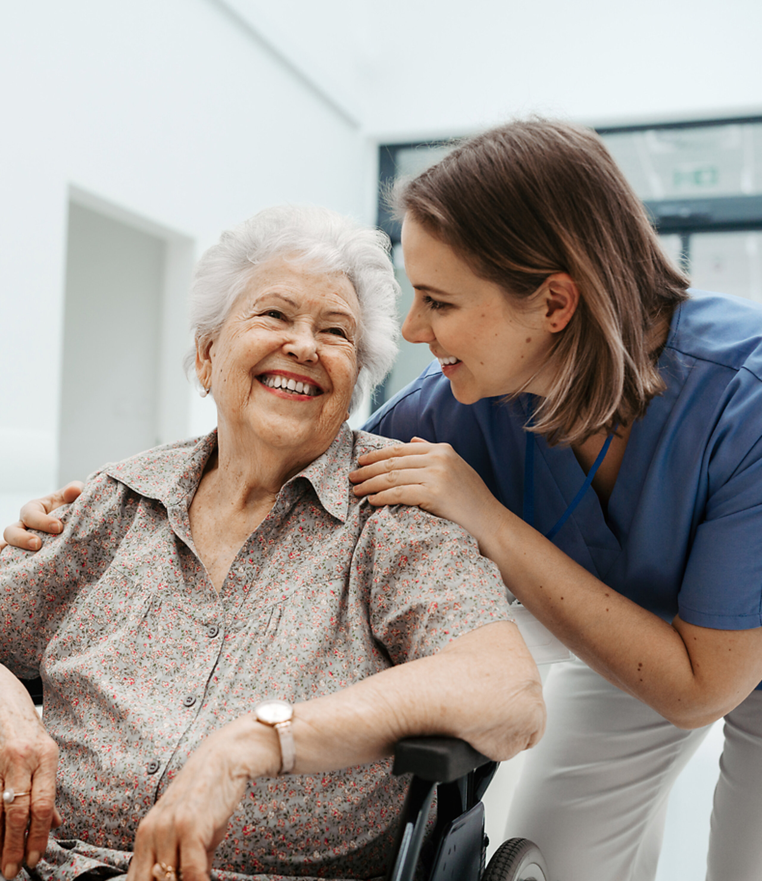 Patientin im Rollstuhl mit Pflegerin Eine ältere Patientin im Rollstuhl wird freundlich von einer Pflegerin betreut.