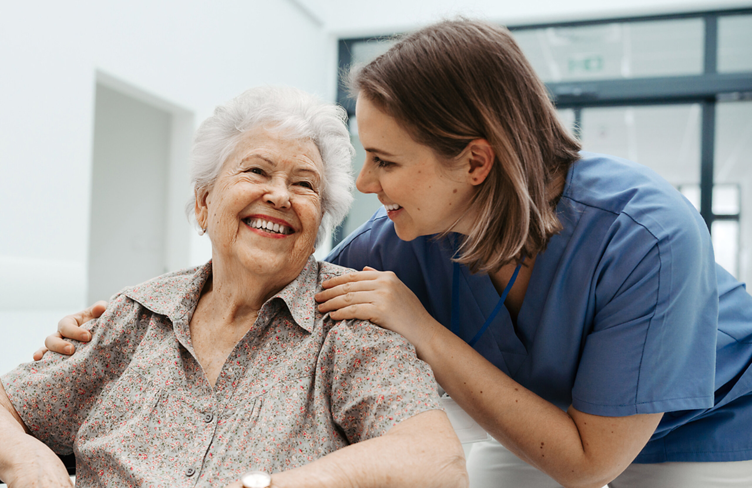 Patientin im Rollstuhl mit Pflegerin Eine ältere Patientin im Rollstuhl wird freundlich von einer Pflegerin betreut.