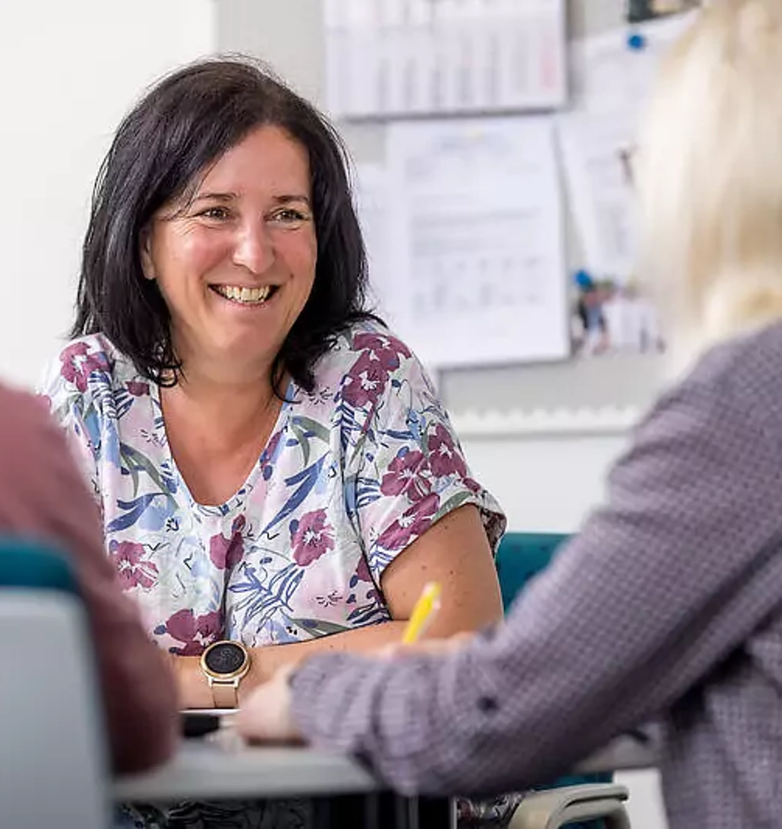 Gespräch Eine Mitarbeiterin unterhält sich mit zwei Patienten am Schreibtisch.