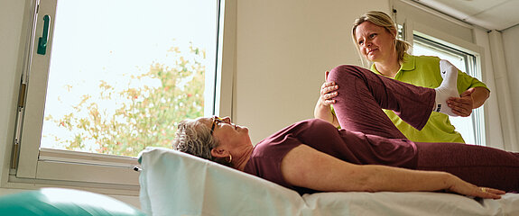 Physiotherapeutin behandelt eine Patientin auf der Liege.