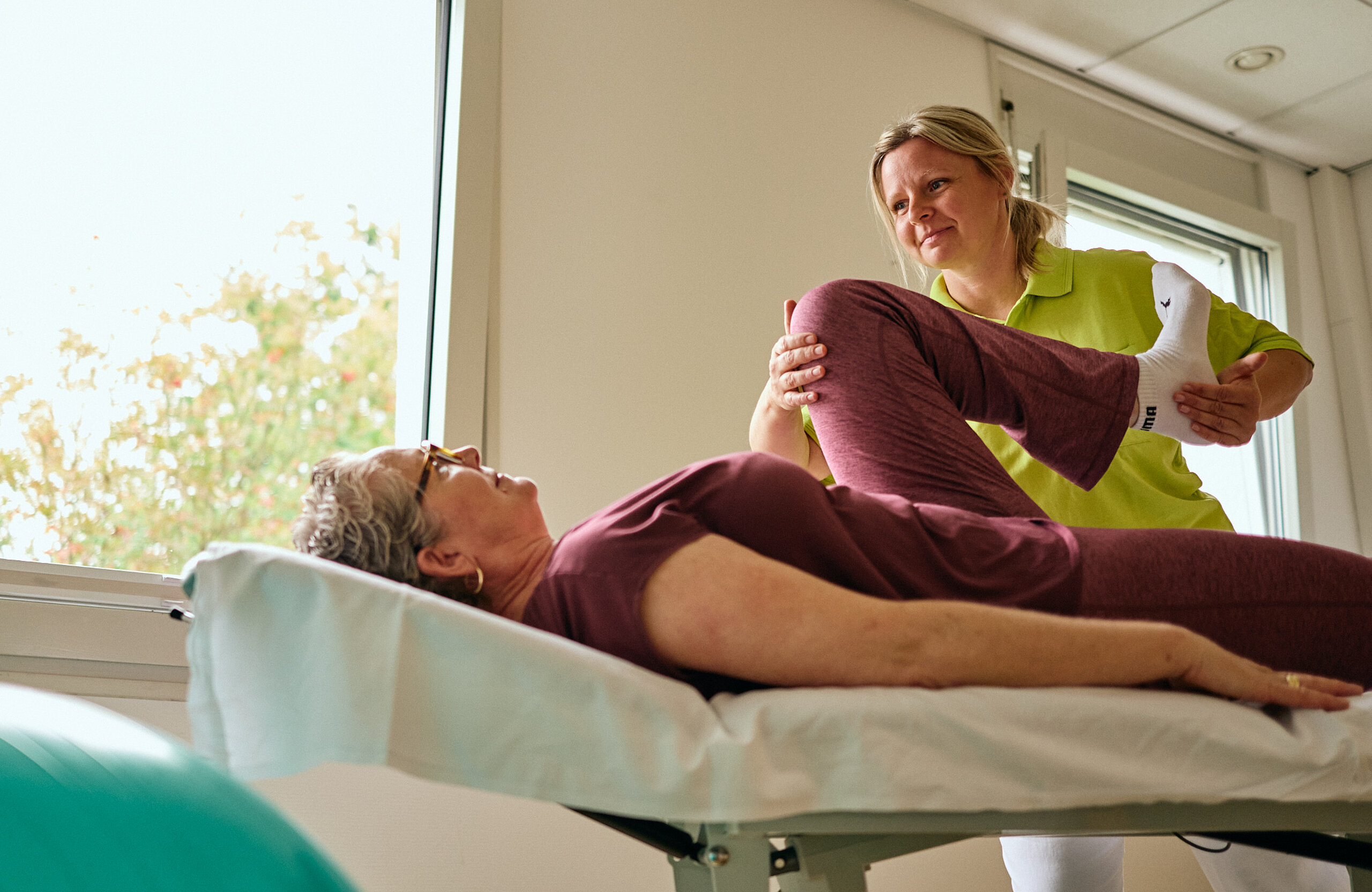 Physiotherapeutin behandelt eine Patientin auf der Liege.