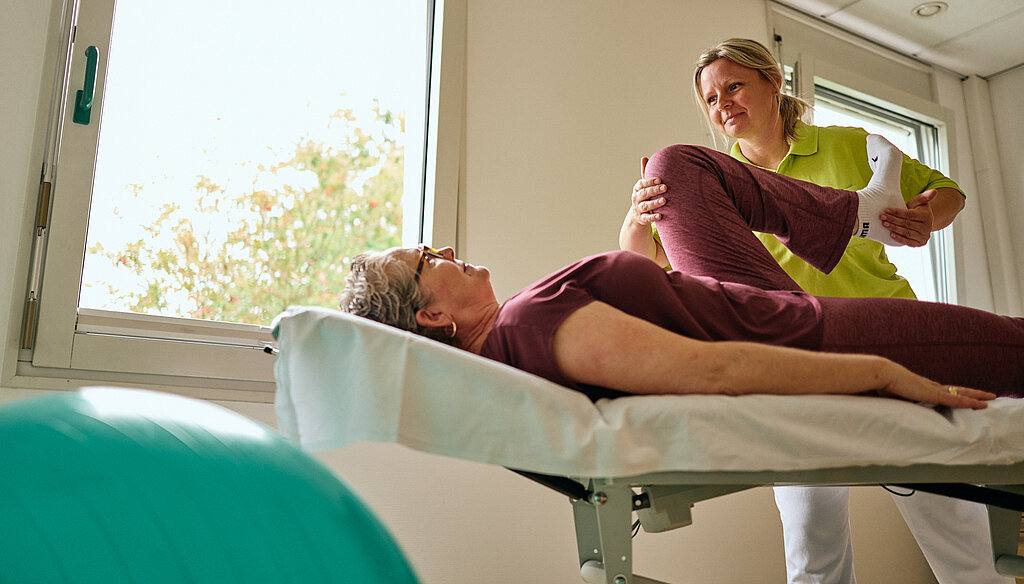 Physiotherapeutin behandelt eine Patientin auf der Liege.