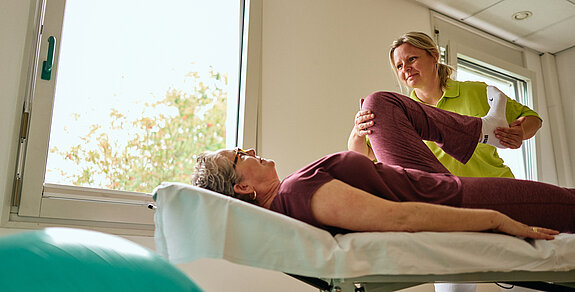 Physiotherapeutin behandelt eine Patientin auf der Liege.