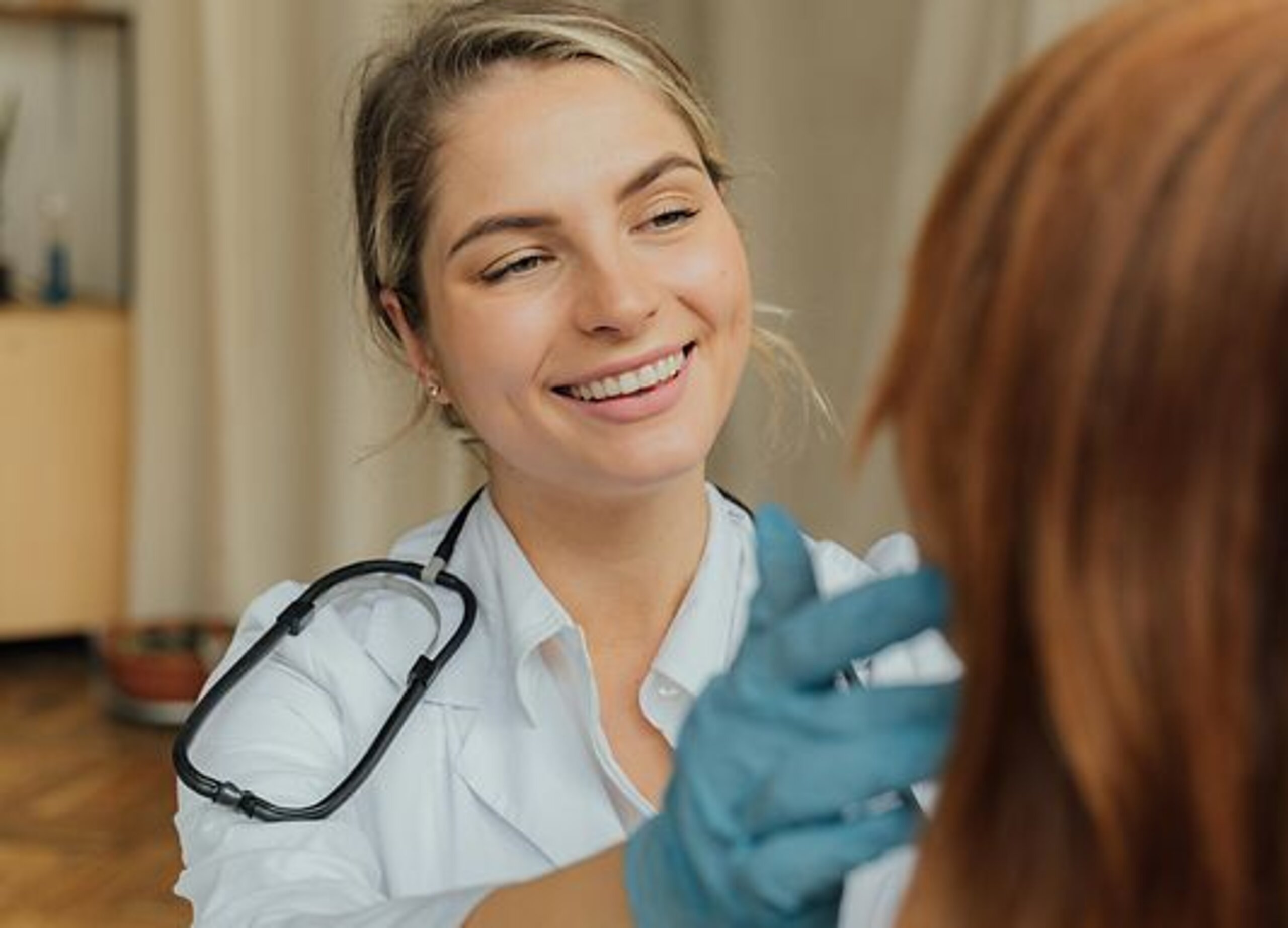 Ärztin Untersuchung Eine freundlich lächelnde Ärztin untersucht eine Patientin.