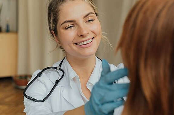 Ärztin Untersuchung Eine freundlich lächelnde Ärztin untersucht eine Patientin.