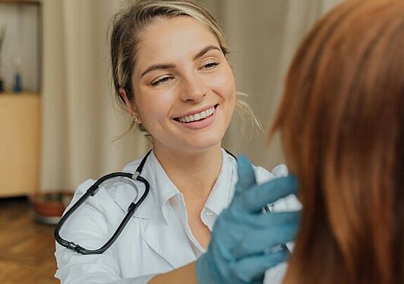 Ärztin Untersuchung Eine freundlich lächelnde Ärztin untersucht eine Patientin.