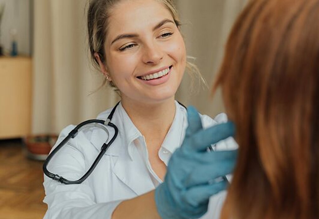 Ärztin Untersuchung Eine freundlich lächelnde Ärztin untersucht eine Patientin.