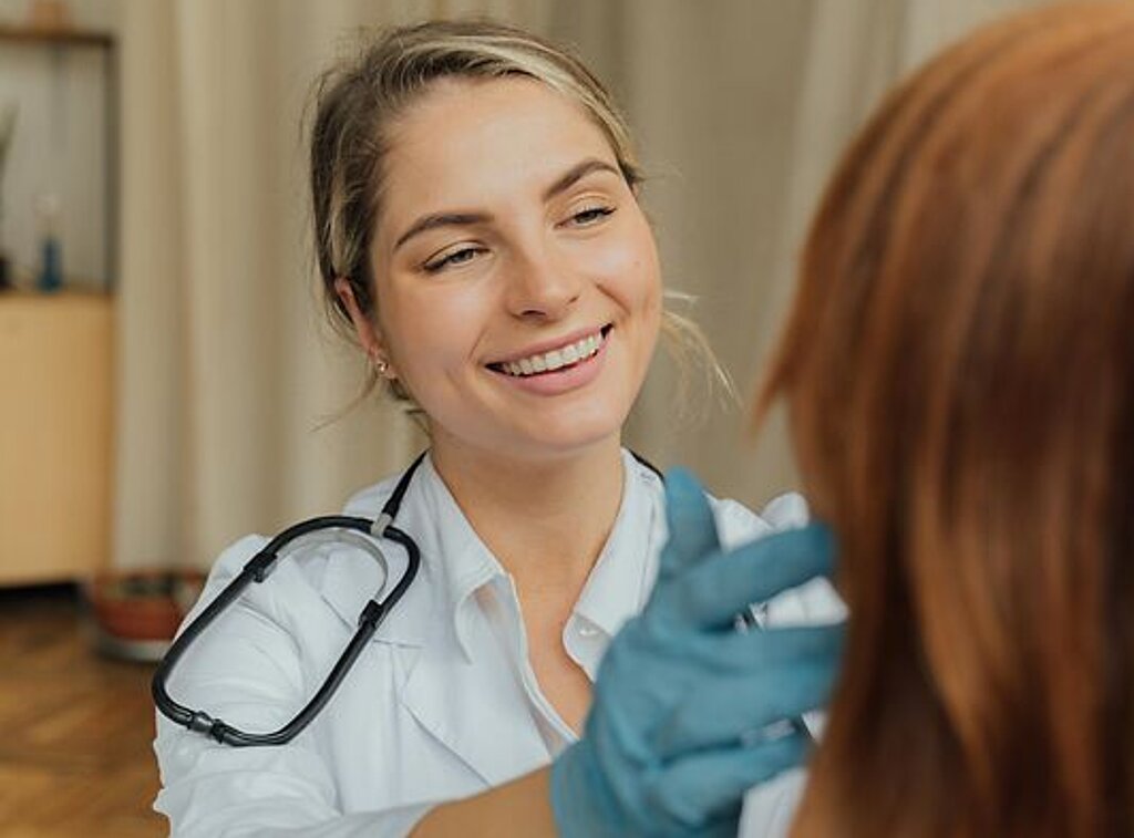 Ärztin Untersuchung Eine freundlich lächelnde Ärztin untersucht eine Patientin.