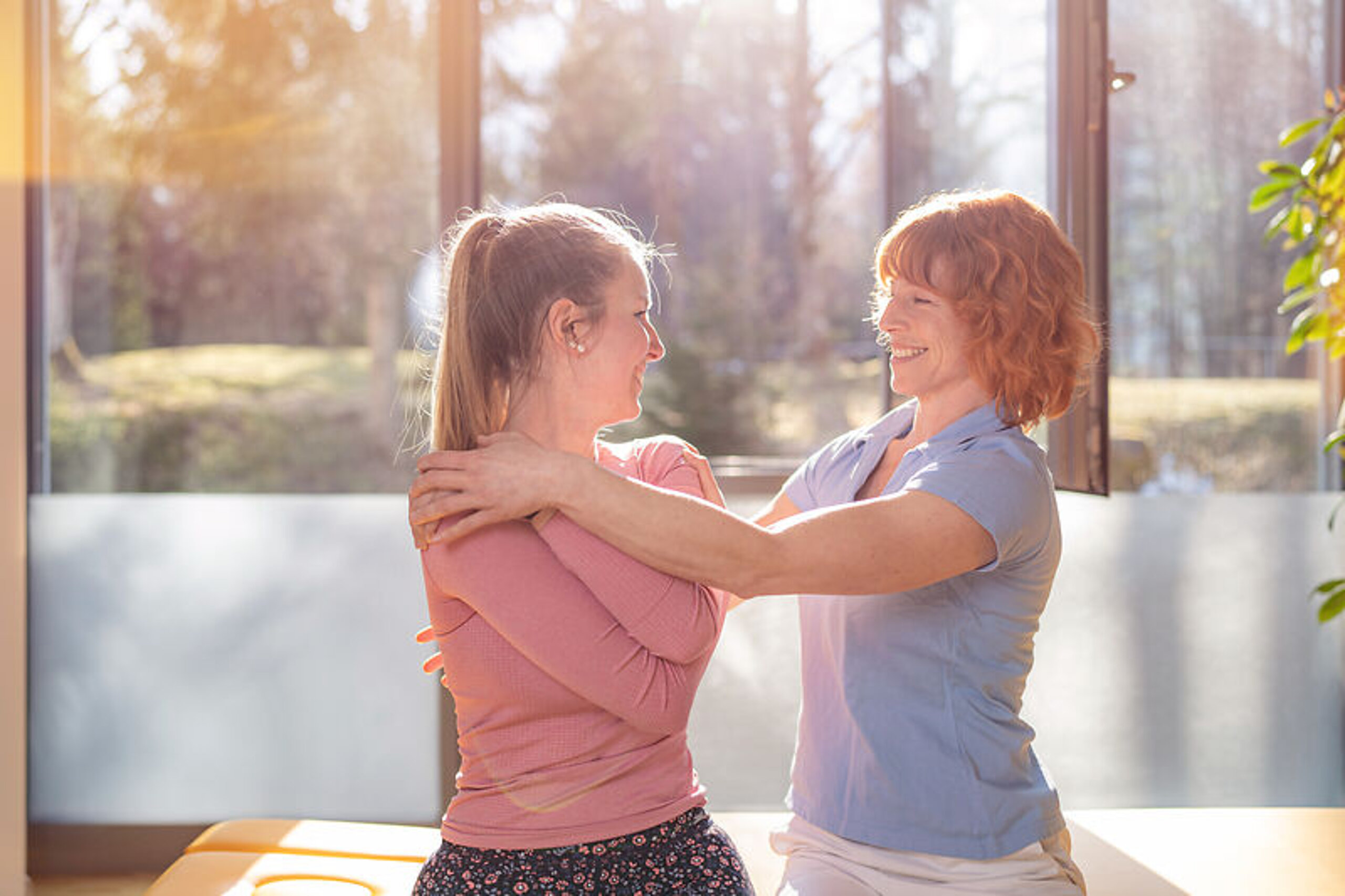 Physiotherapie Eine Therapeutin behandelt eine junge Patientin im Sitzen.