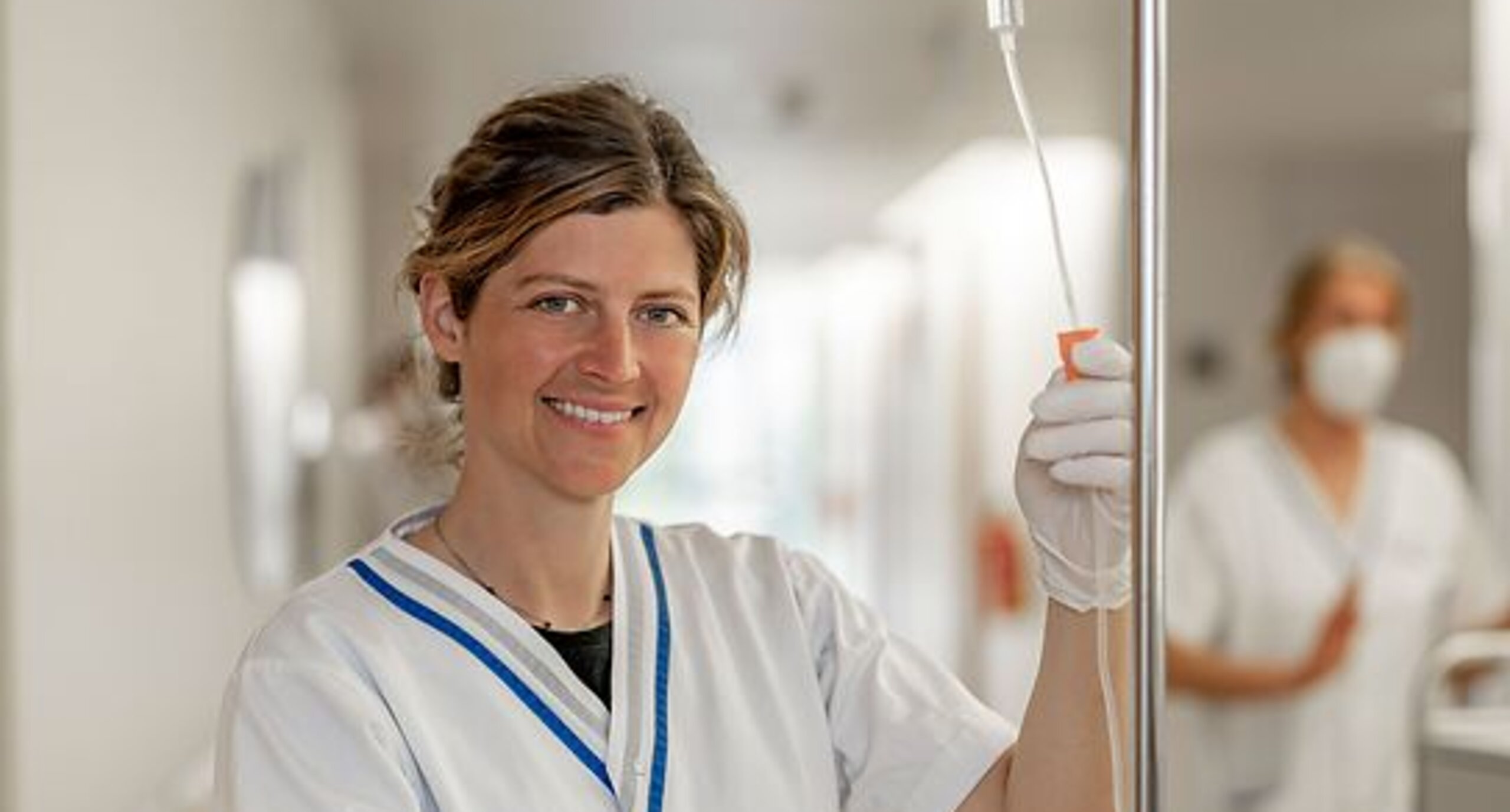 Pflege Infusion Eine Pflegerin steht mit einem Infusionsgerät im Gang einer Klinik.