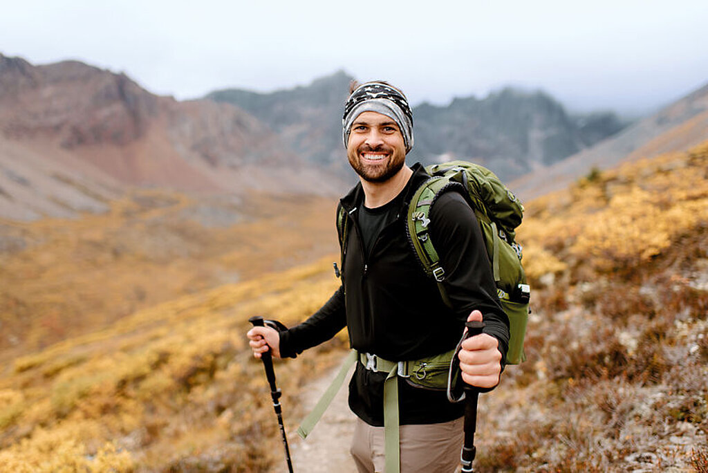 Wanderung Berge Ein junger Mann wandert mit Stöcken in den Bergen.