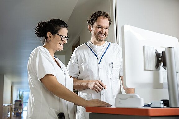 Pflegeteam am Bildschirm Zwei Pflegekräfte arbeiten gemeinsam an einem digitalen Visitenwagen.