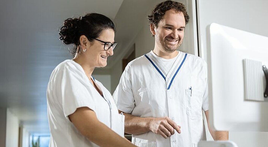 Pflegeteam am Bildschirm Zwei Pflegekräfte arbeiten gemeinsam an einem digitalen Visitenwagen.