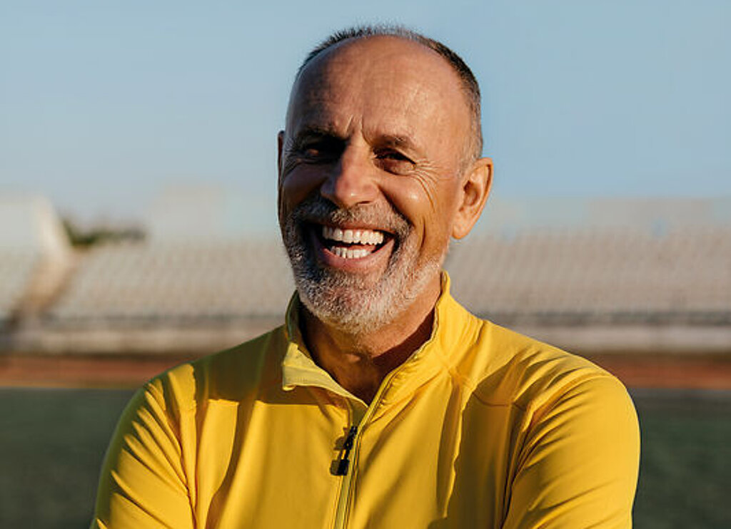 Mann lachend Ein Mann im Rentenalter lacht freundlich im Fußballstadion.