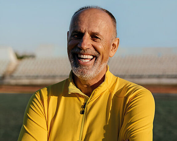 Mann lachend Ein Mann im Rentenalter lacht freundlich im Fußballstadion.