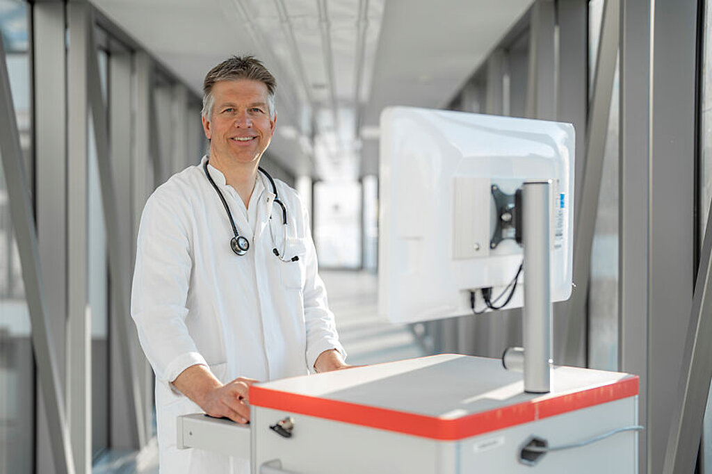 Arzt mit Visitenwagen Ein lächelnder Arzt mit Visitenwagen im Gang.