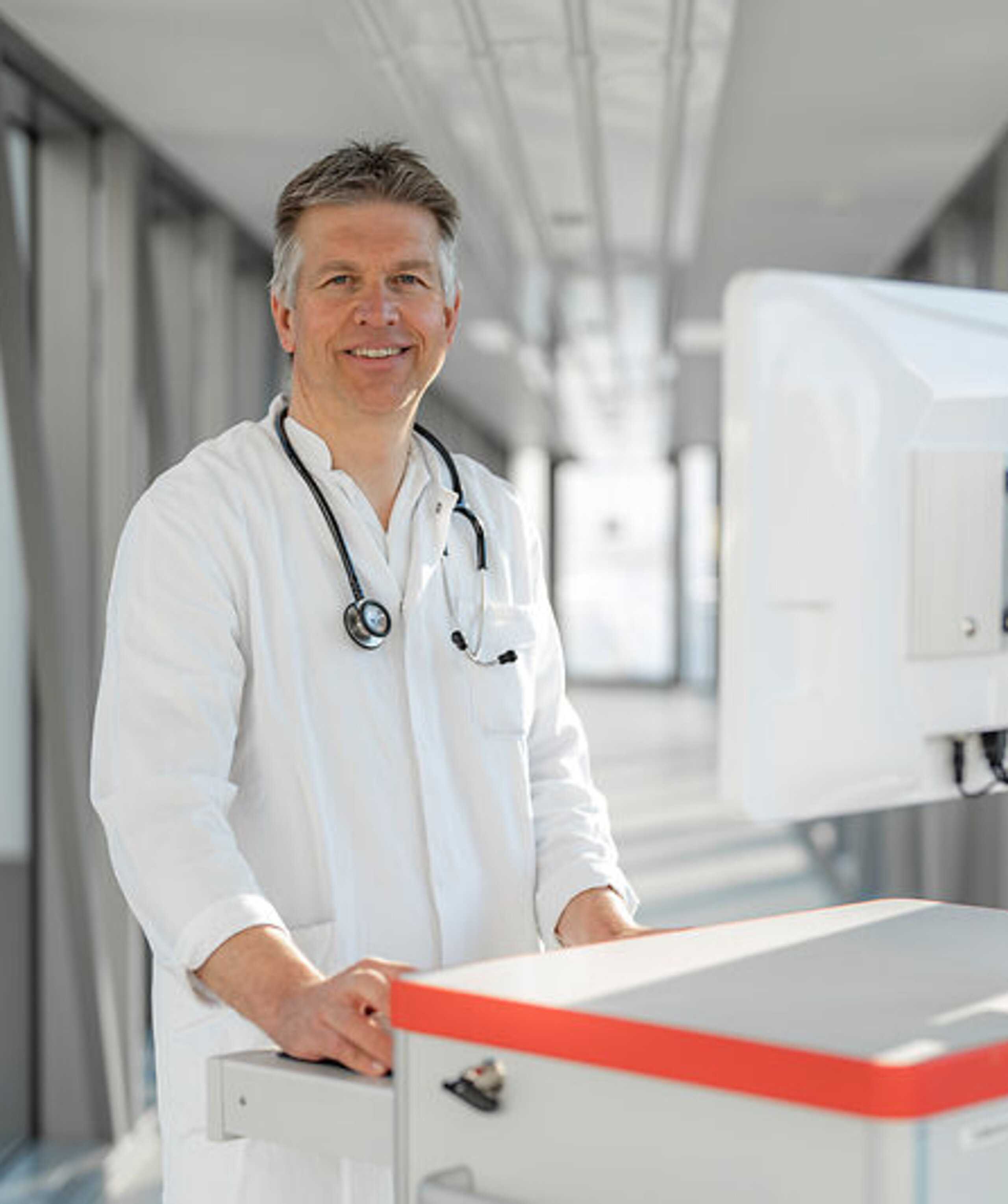 Arzt mit Visitenwagen Ein lächelnder Arzt mit Visitenwagen im Gang.