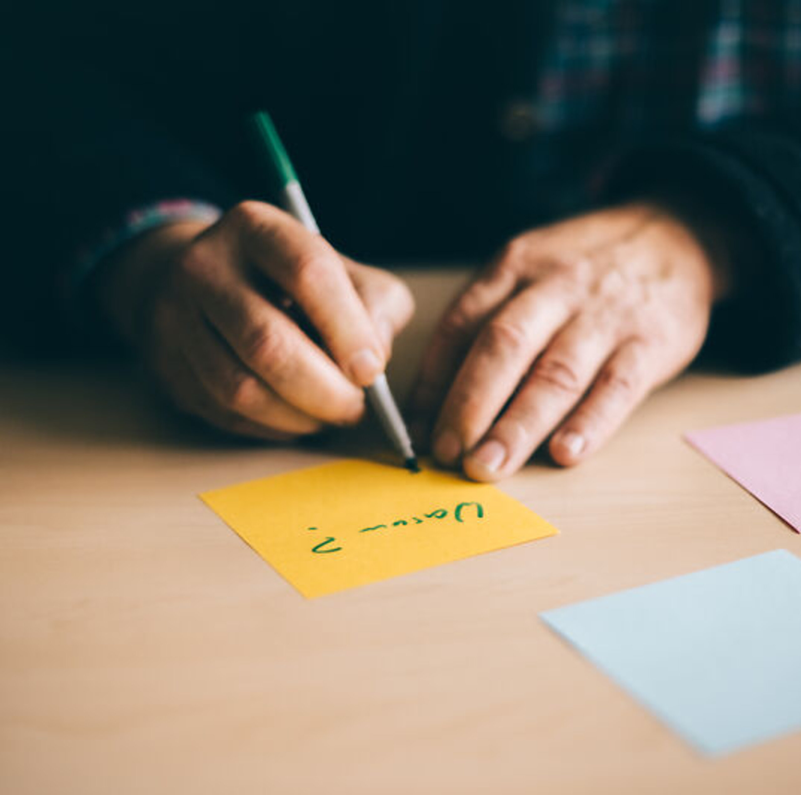 Psychologie Jemand schreibt innerhalb einer Psychotherapie etwas auf mehrere bunte Zettel.