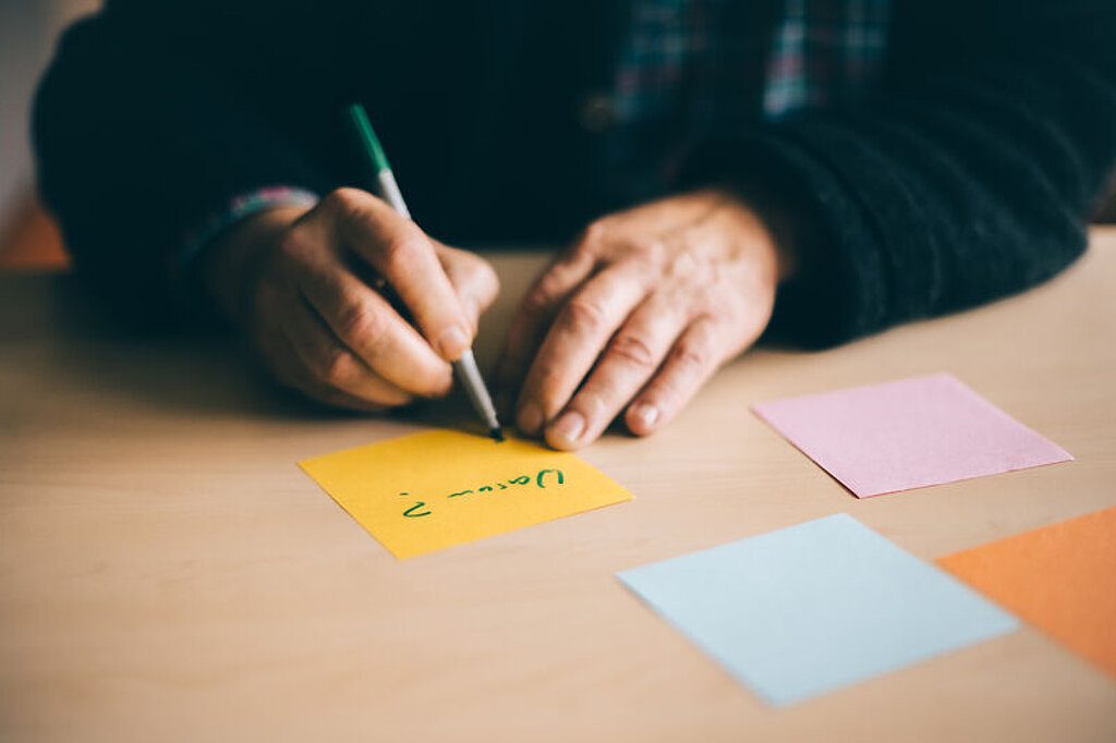 Psychologie Jemand schreibt innerhalb einer Psychotherapie etwas auf mehrere bunte Zettel.