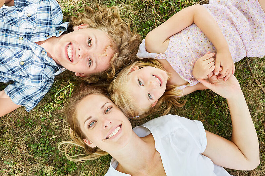 Mutter mit Kindern Eine Mutter liegt mit zwei Kindern auf einer Wiese.