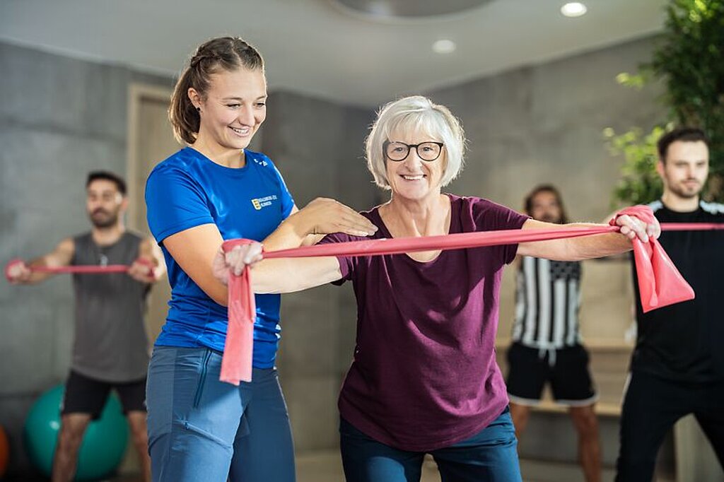 Menschlichkeit Eine Therapeutin unterstützt eine Patientin bei einer Fitnessübung.