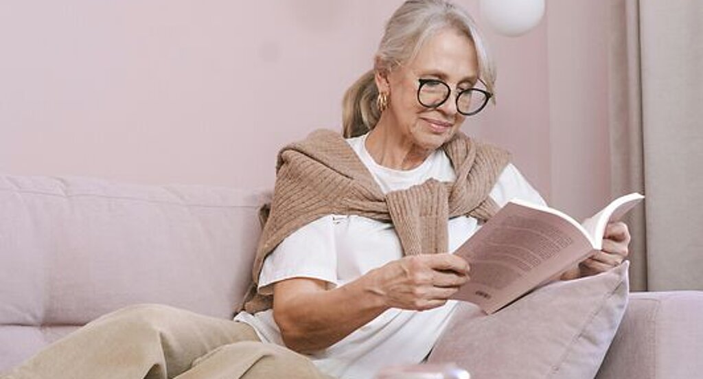 Frau ließt ein Buch Eine Frau ließt zuhause ein Buch auf dem Sofa.