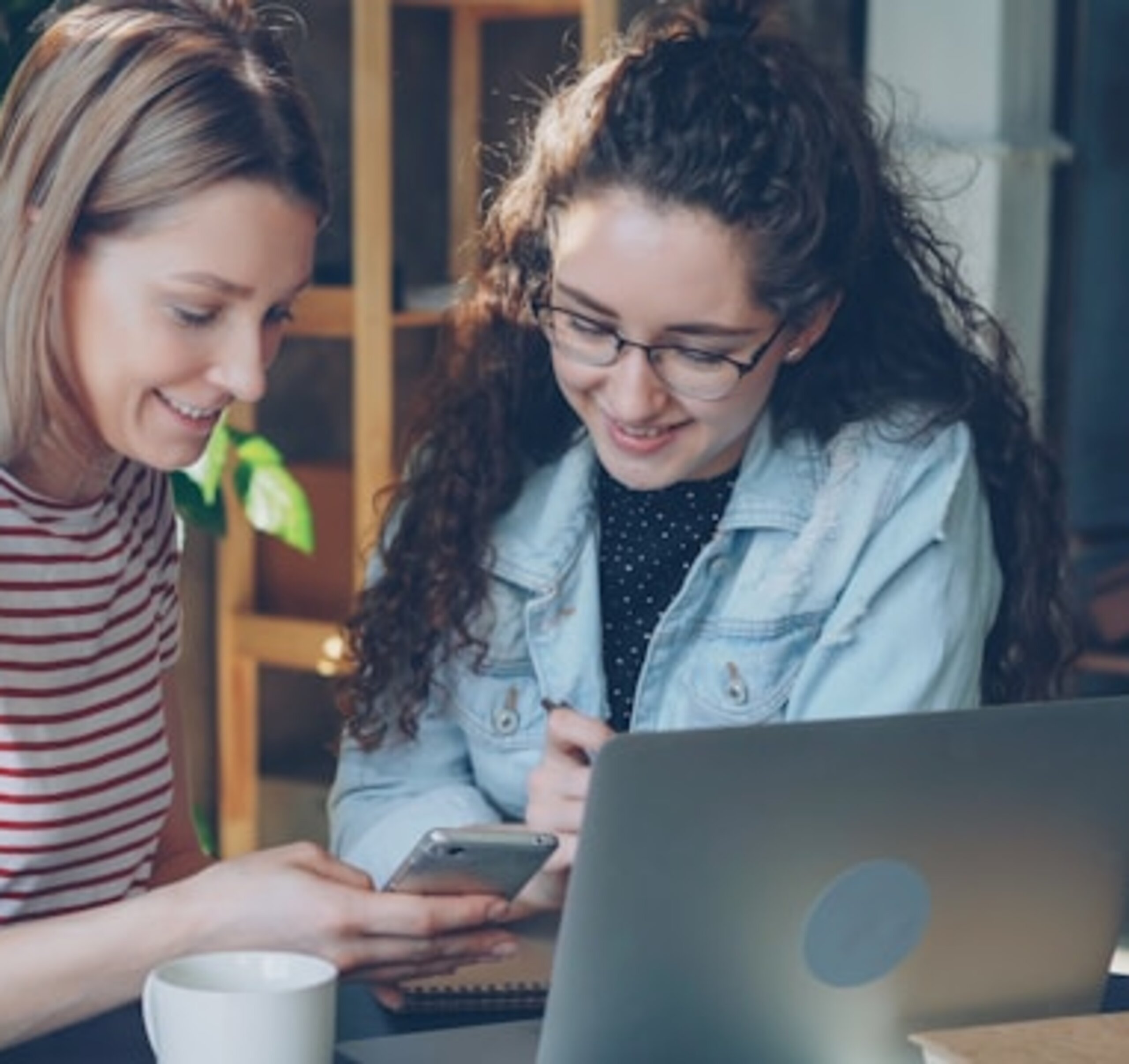 Studentinnen Zwei Studentinnen schauen gemeinsam in einen Laptop und ein Smartphone.