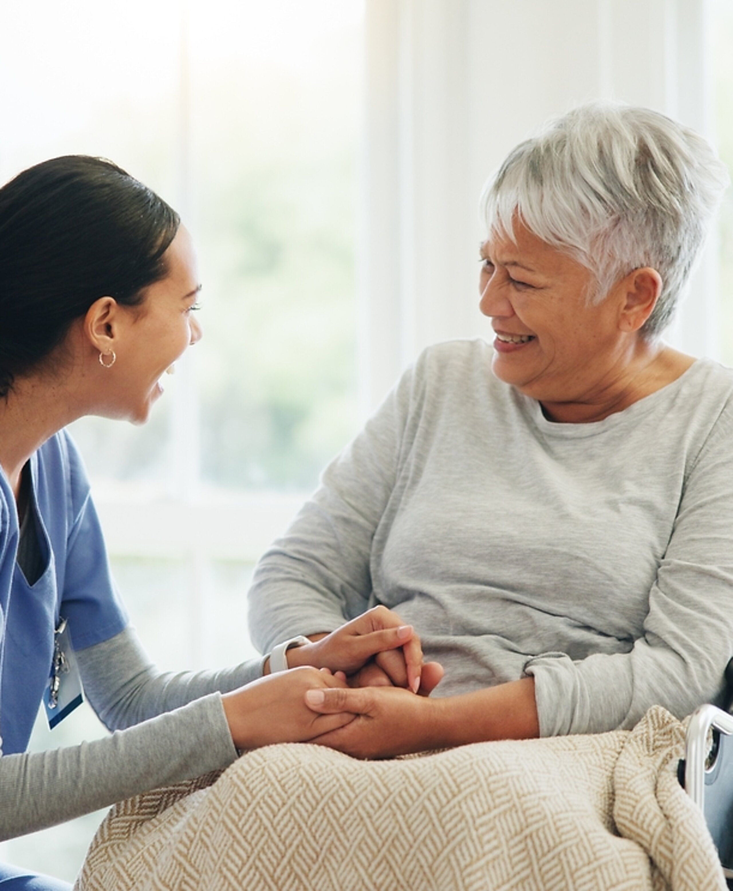 Pflegerin mit Patientin Eine Pflegerin hält vertrauensvoll die Hand einer Patientin im Rollstuhl.