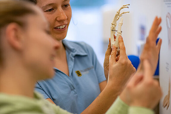 Ergotherapie Handmodel Eine Ergotherapeutin erklärt etwas an einem Handmodel.